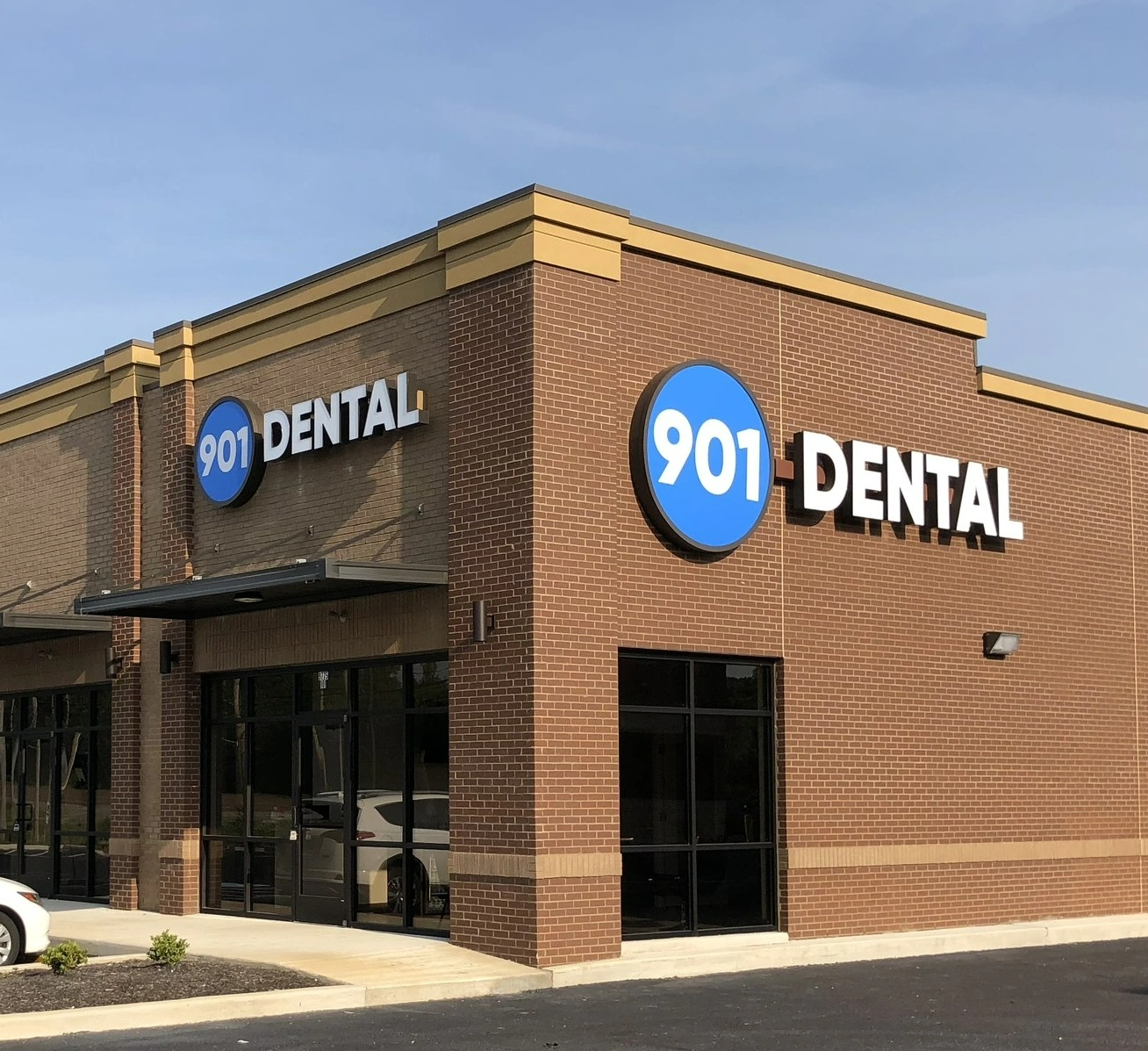 901 Dental storefront exterior with brick building and blue circular logo signage.