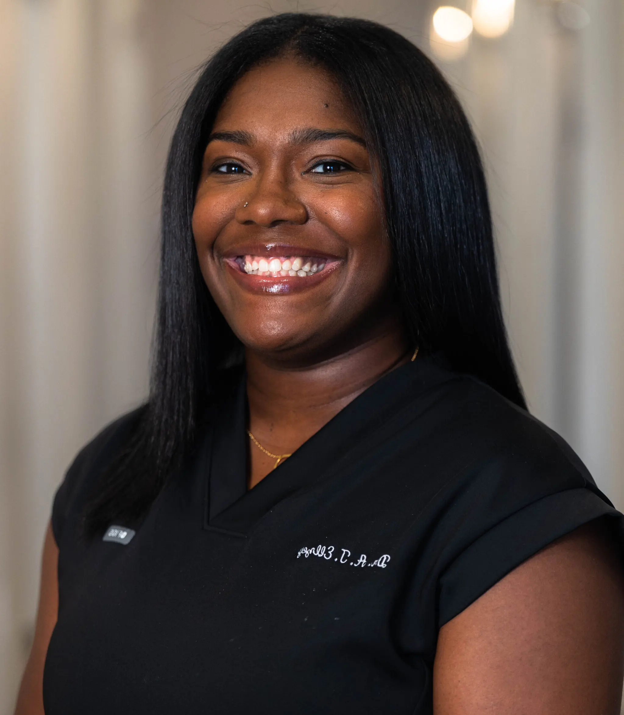 Professional dental staff member smiling at 901 Dental in black scrubs.